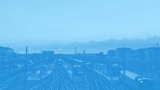 Skyline einer Stadt, im Vordergrund Schienen.